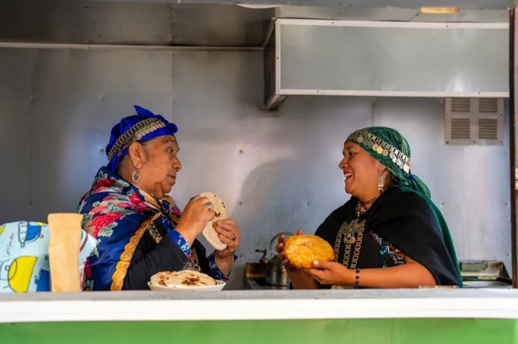 02two indigenous mapuche women preparing and selling traditional chilean flatbread from a food